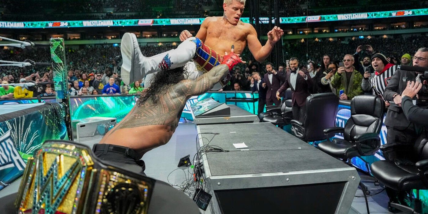 WWE Champion Roman Reigns attacks Cody Rhodes on an announce table at WrestleMania XL