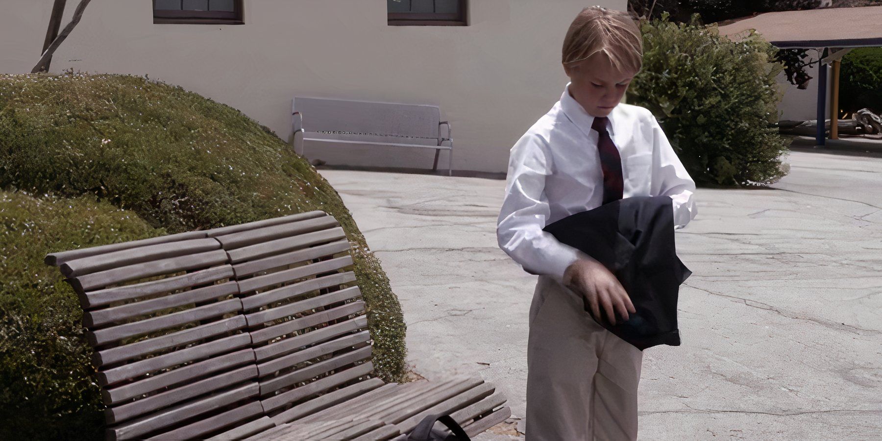 A boy in a school uniform folds his blazer in Sons of Anarchy