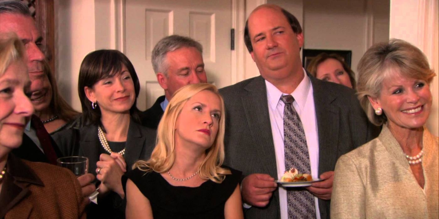 Angela (Angela Kinsey) and Kevin (Brian Baumgartner) standing with a group looking annoyed in The Office.