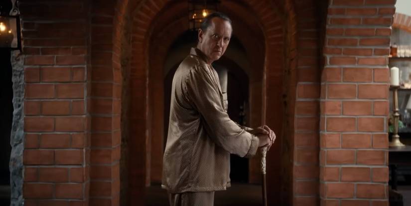 Odell Leopold (Richard Grant) leaning on his cane in Death of a Unicorn.