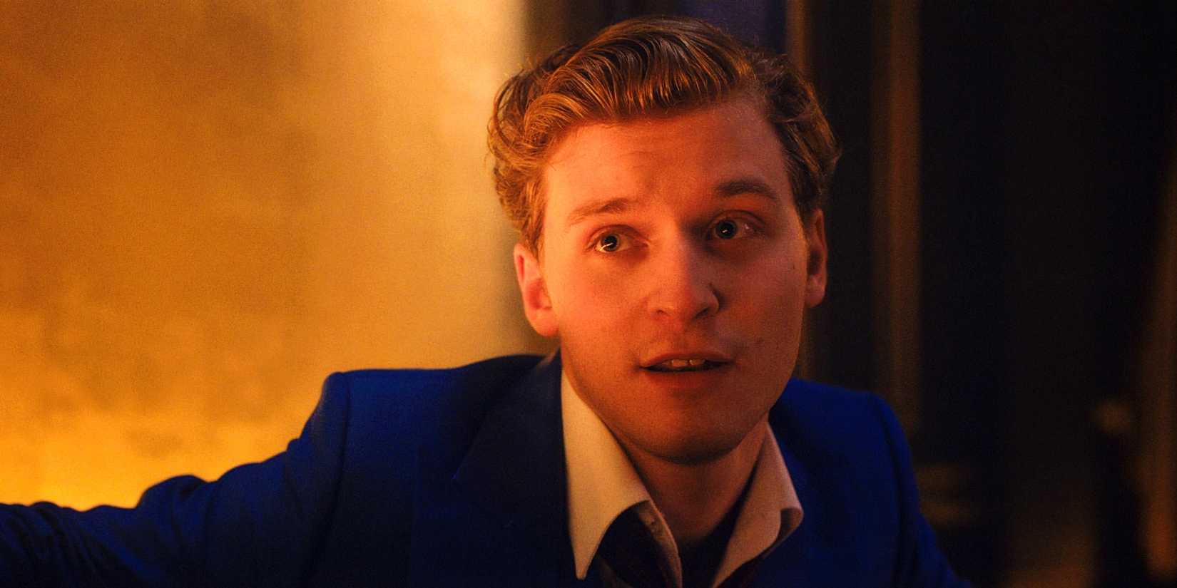 Fred Hechinger as Dmitri Smerdyakov sitting in a booth in his club in Kraven The Hunter