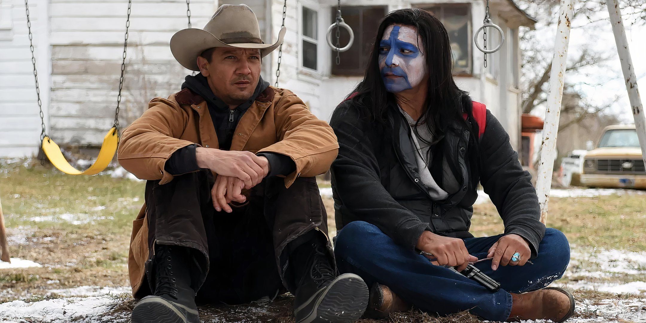 Gil Birmingham's Martin in face paint looking at Jeremy Renner's Cory while sitting on the ground in Wind River