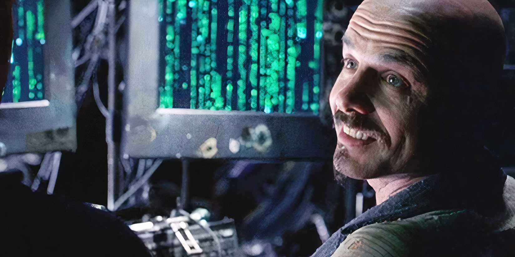 Joe Pantoliano as Cypher smiling by his computer in in The Matrix.