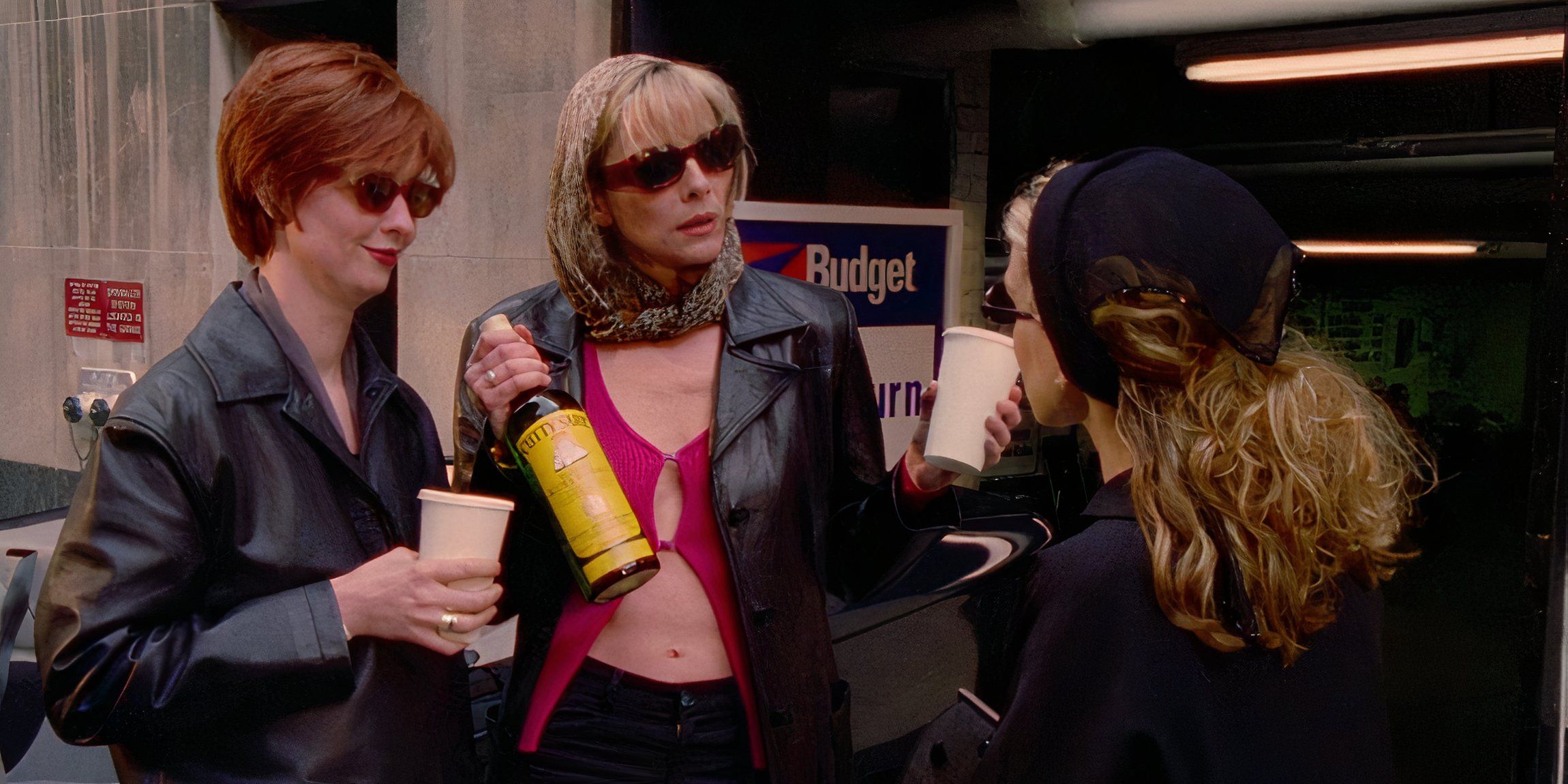 Miranda with a coffee cup and Samantha with a bottle of booze while they talk to Carrie while heading to a baby shower in Sex and the City