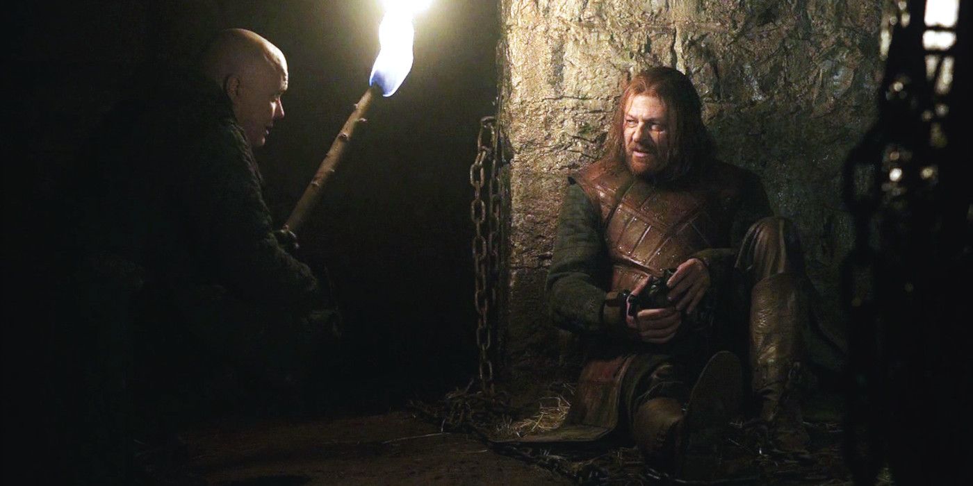 Lord Varys holding a torch and visiting Ned Stark in the dungeon in Game of Thrones season 1