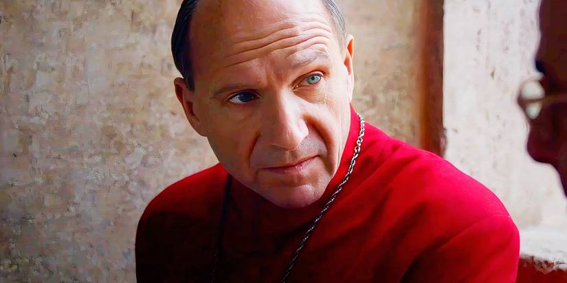 Ralph Fiennes as Cardinal Lawrence looking over at Stanley Tucci in Conclave