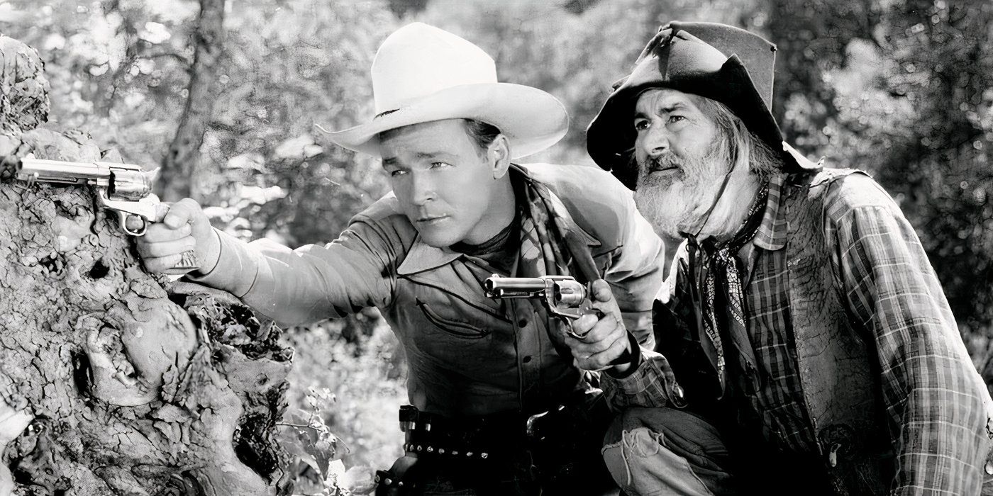 Roy Rogers e Gabby Hayes atrás de uma colina com suas armas em punho