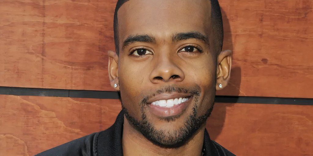 Singer Mario Smiling In Front Of A Wooden Wall