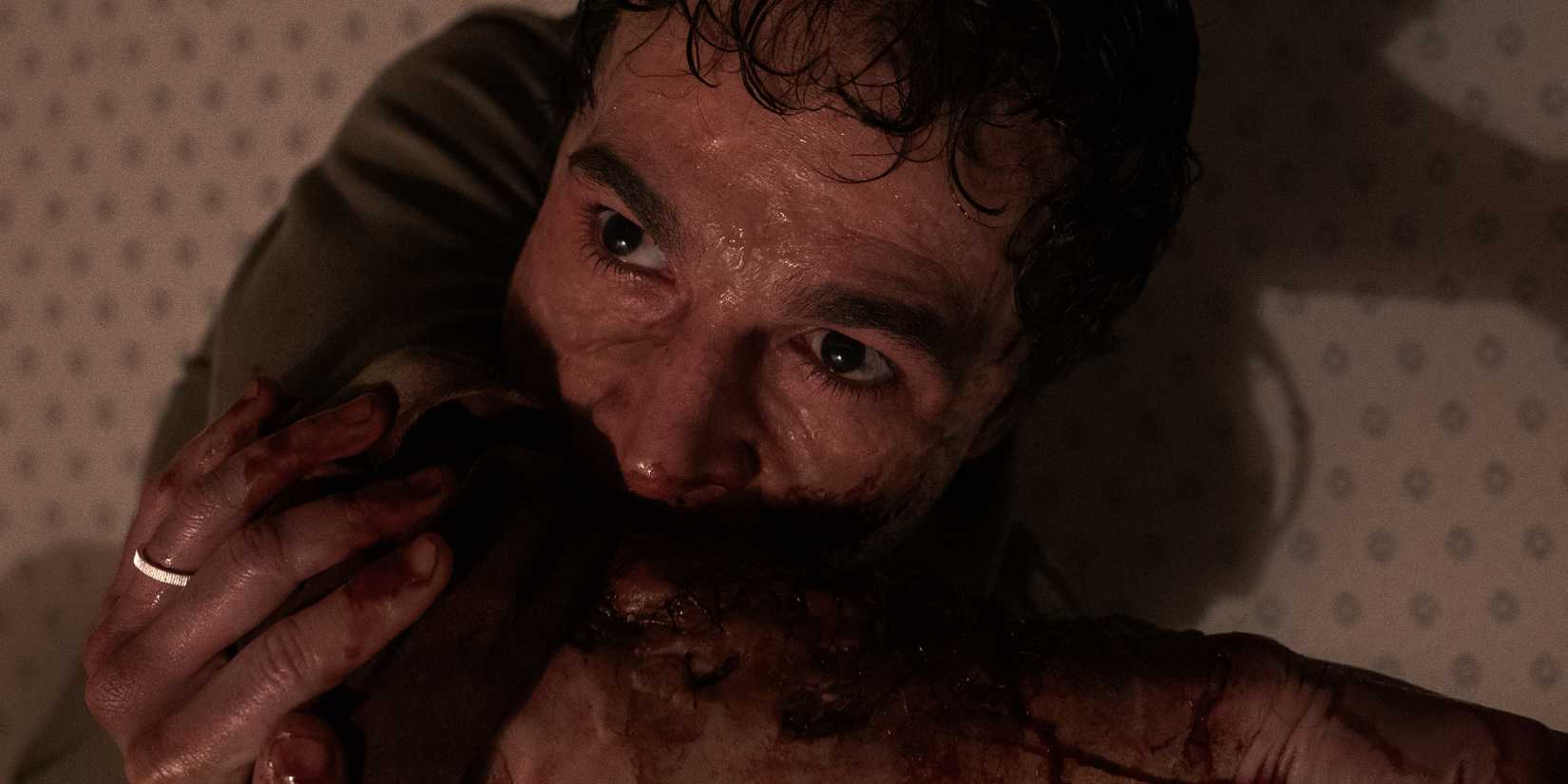 A close-up of Blake aggressively biting his own arm in Wolf Man