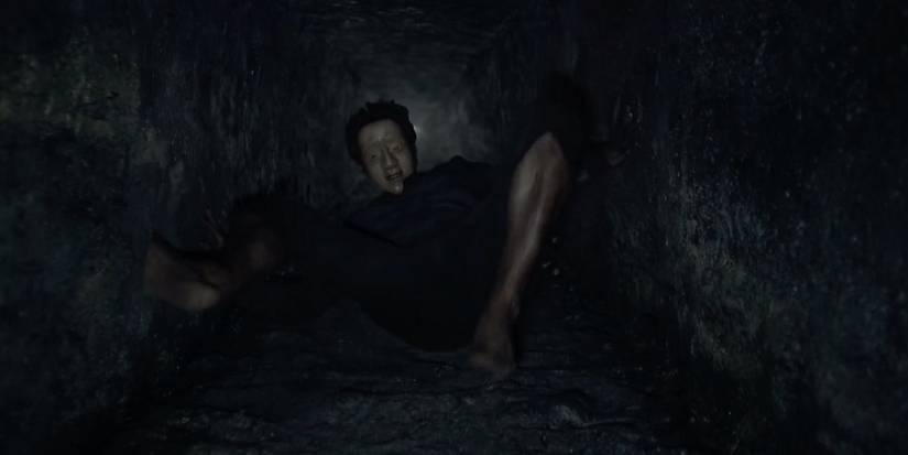 A masked man climbing up a well in The Fall.