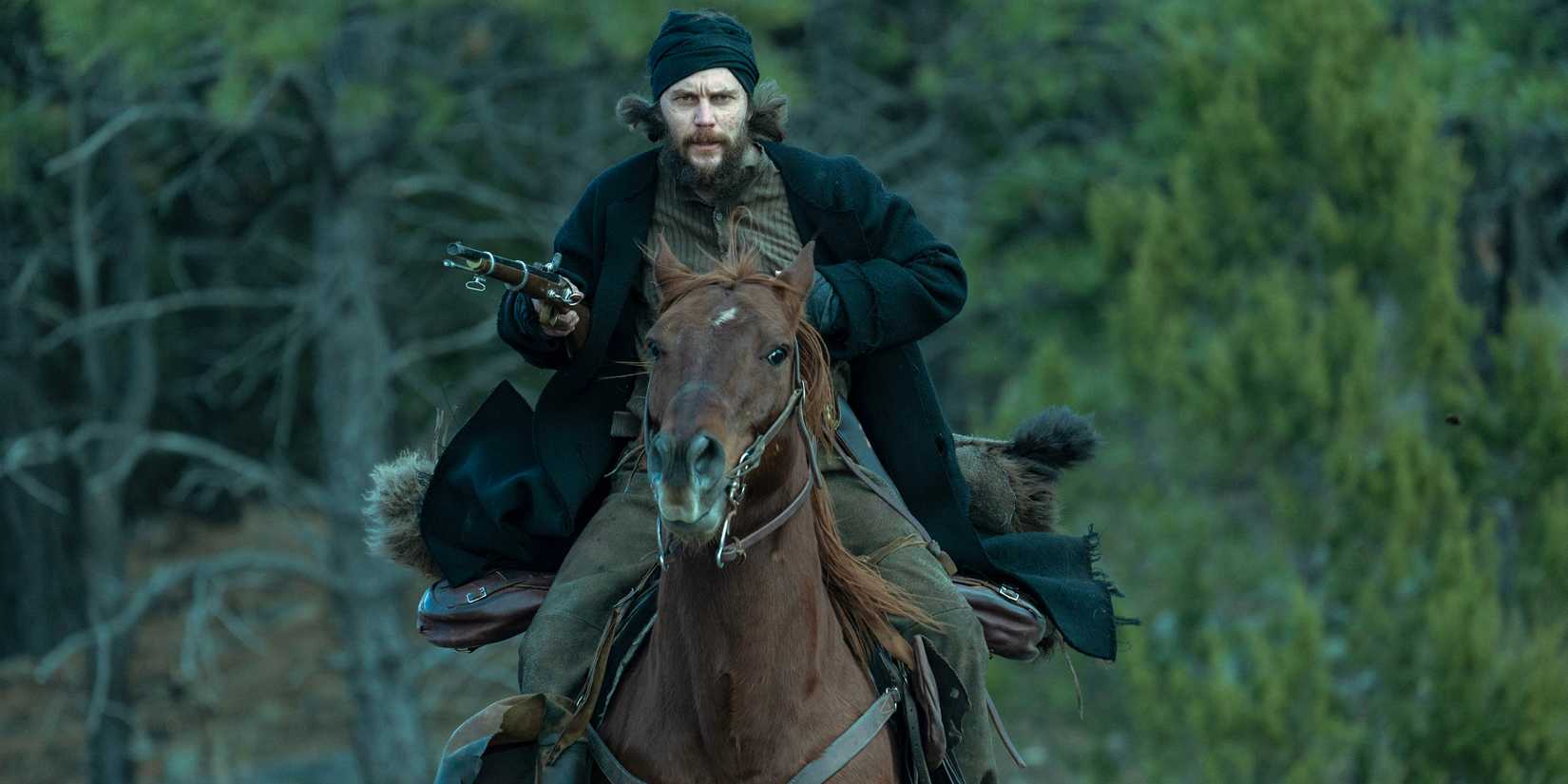 Taylor Kitsch's Isaac riding on a horse with his gun drawn in American Primeval