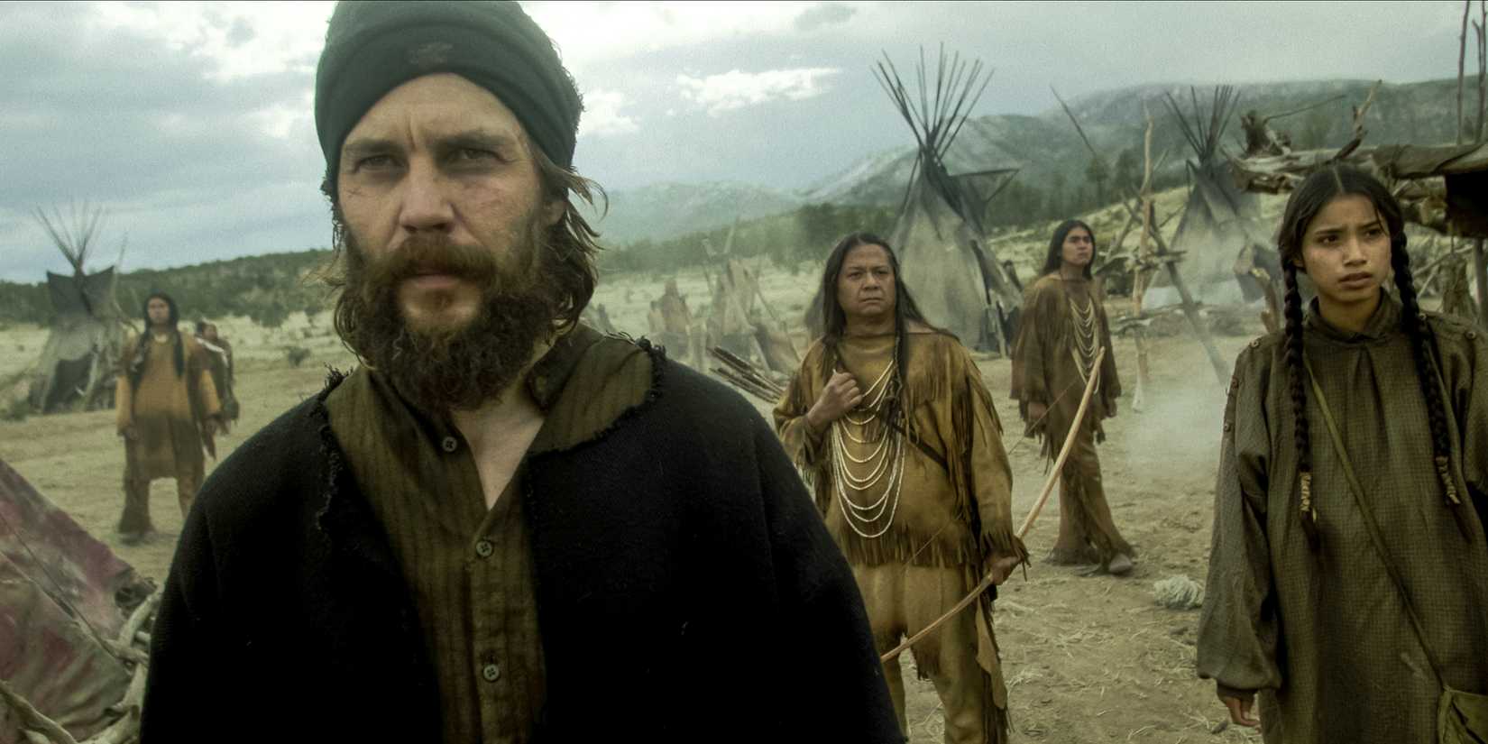 Taylor Kitsch's Isaac looking intensely at someone while in a Paiute camp in American Primeval