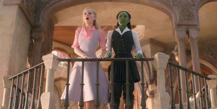 Ariana Grande as Glinda and Cynthia Erivo as Elphaba standing on a balcony in Wicked