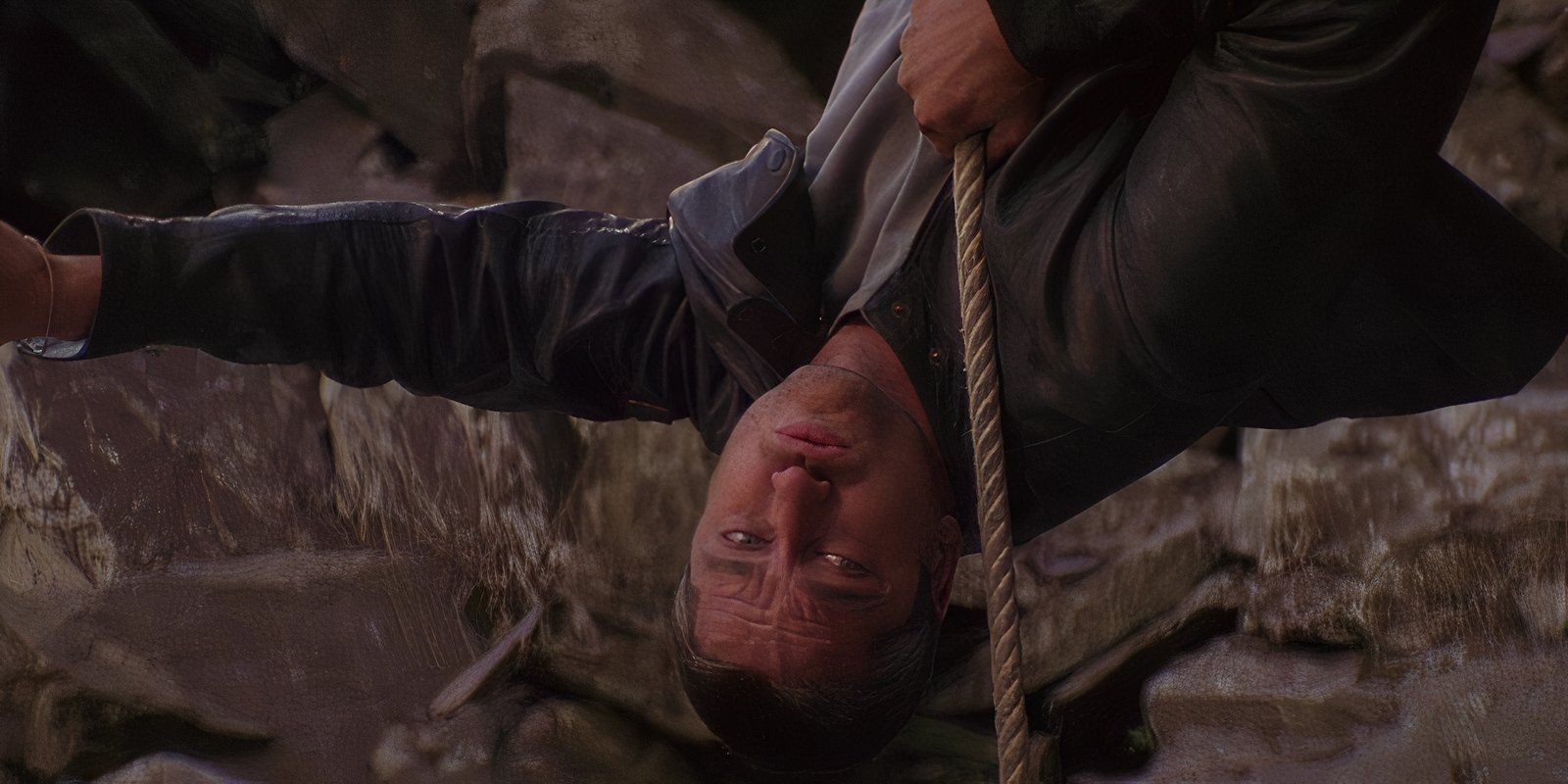 Gerard Butler hanging upside down from a rope with a gun in Lara Croft 2