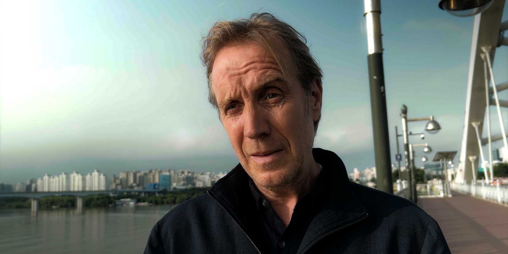 Rhys Ifans as Sam looking intensely while standing on a road bridge in Inheritance