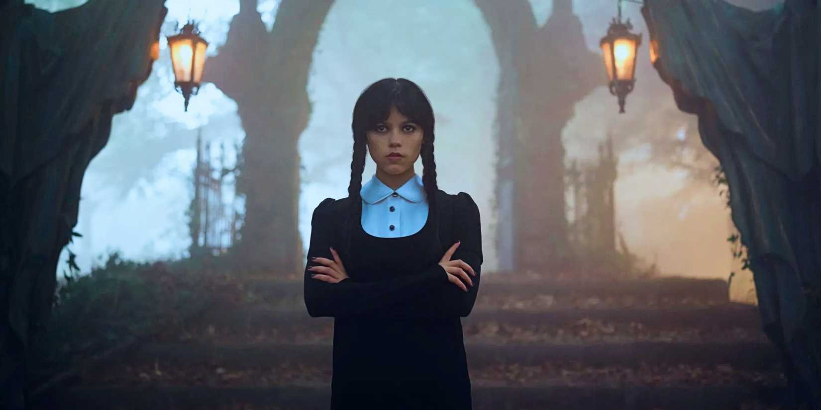 Jenna Ortega as Wednesday Addams standing with her arms crossed in the woods in Wednesday season 2