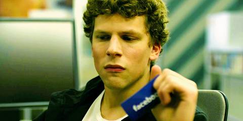 Jesse Eisenberg as Mark Zuckerberg looking sad while holding onto a Facebook card in The Social Network
