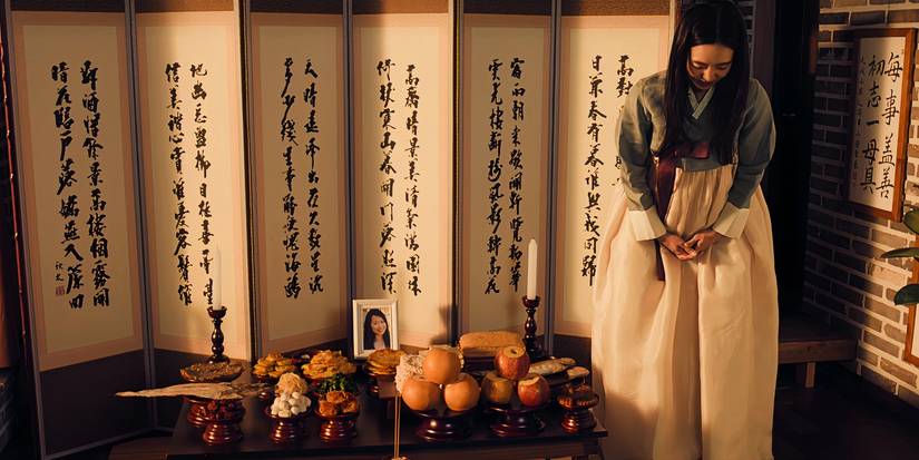 Jiwan bows her head while standing next to a jesa alter in XO, Kitty Season 2