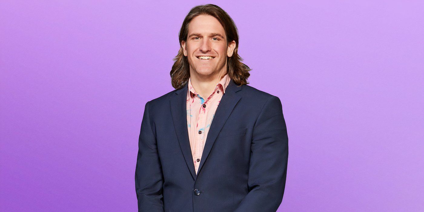 Love is the Blind Season 8 Joey Leveille smiling, wearing a marine suit and a pink shirt against a purple background.