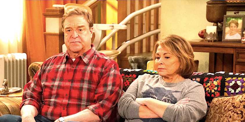John Goodman's Dan and Roseanne Barr's Roseanne looking annoyed sitting on a couch in Roseanne season 10