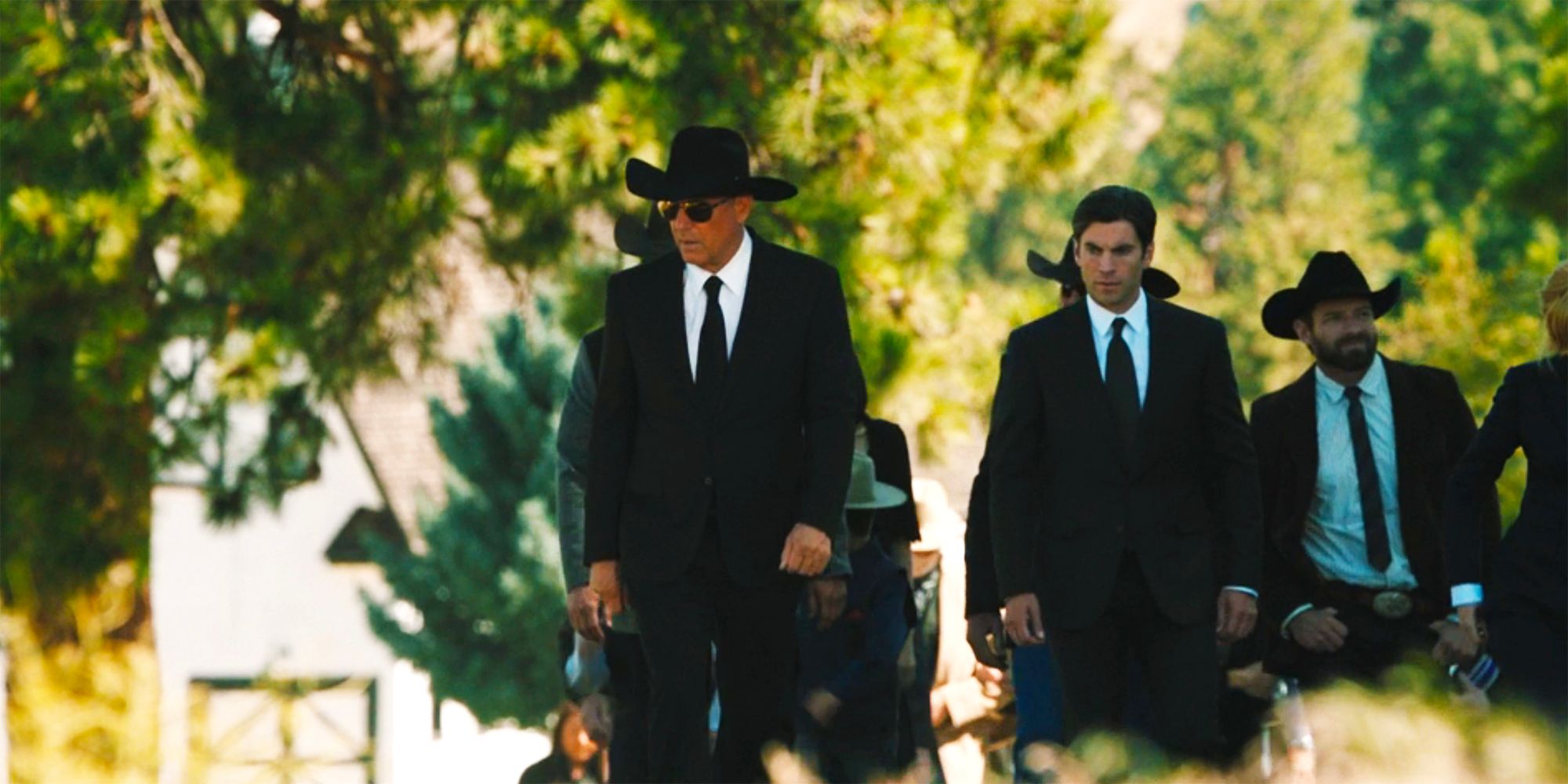 John walking with a funeral procession after Lee Dutton's funeral in Yellowstone