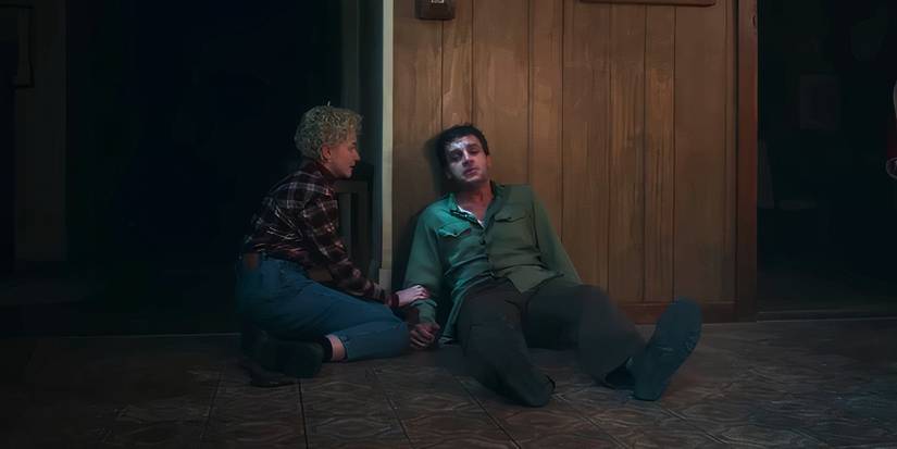 Julia Garner seated on the floor next to an ailing Christopher Abbott in Wolf Man