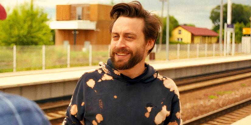 Kieran Culkin smiling while at the train station in A Real Pain