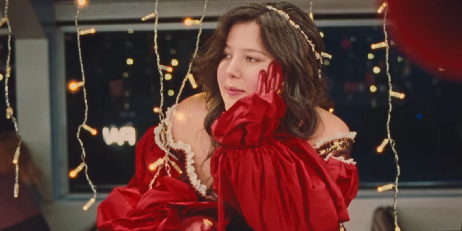 Lucy Dacus in a red dress surrounded by led string light in the &ldquo;Ankles&rdquo; music video