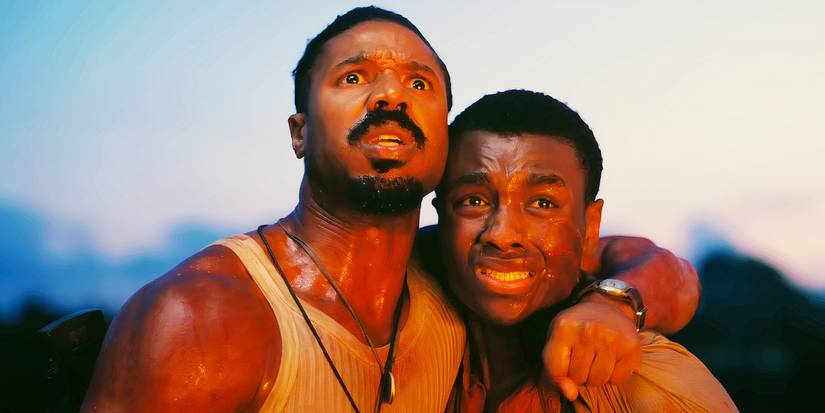 Michael B Jordan with his arm around another man while looking up at the sky in terror in Sinners