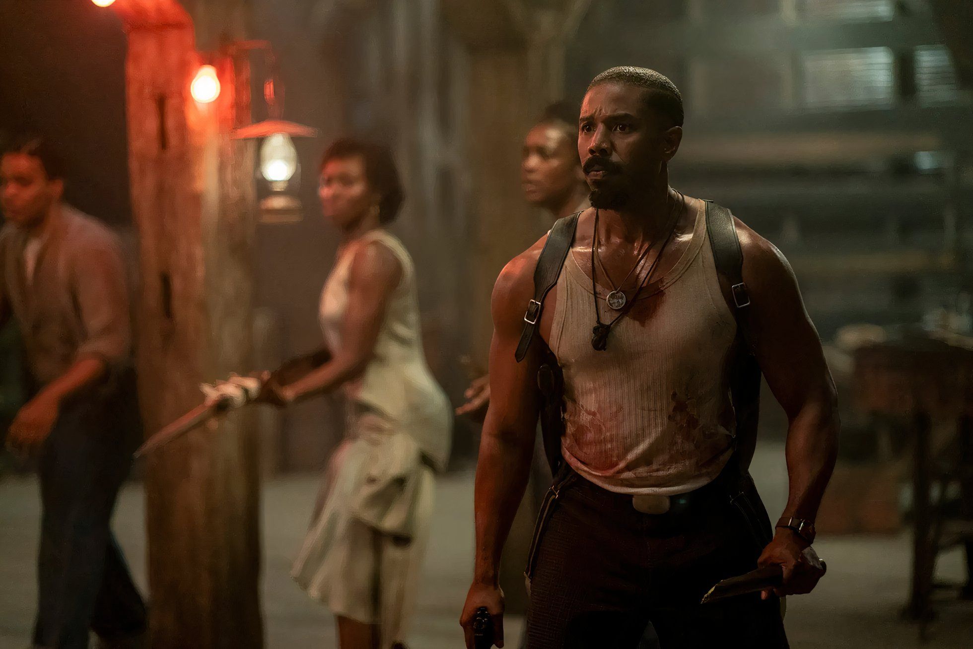 Michael B. Jordan tenant un pieu en bois et un pistolet dans le film 