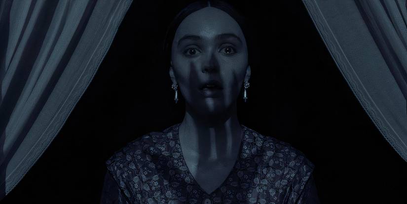 Lily-Rose Depp looks terrified with Orlok's shadow over her face in Nosferatu.