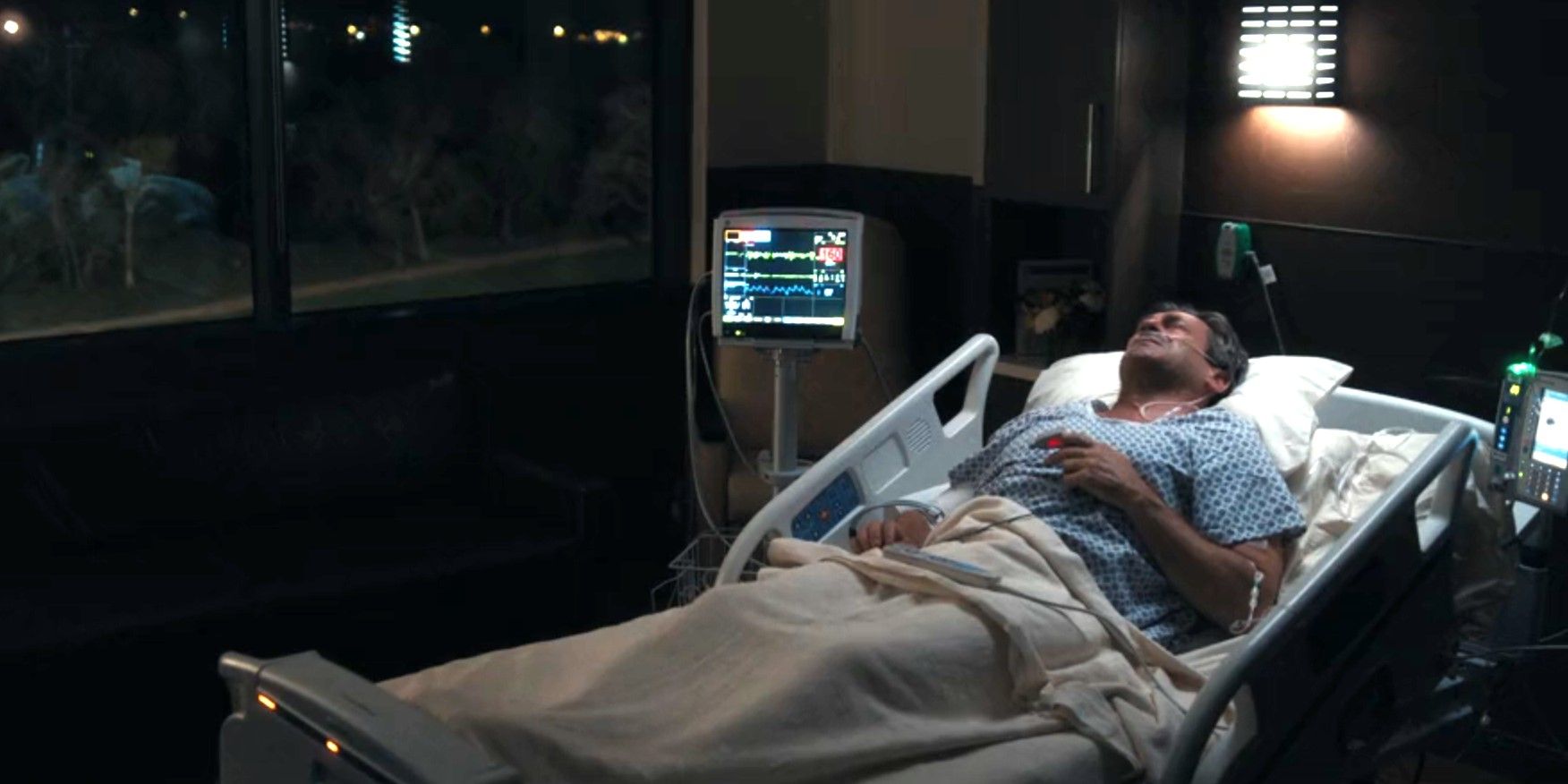 Monty Miller (Jon Hamm) giace in un letto d'ospedale quando la sua frequenza cardiaca aumenta nella prima stagione di Landman, episodio 9.