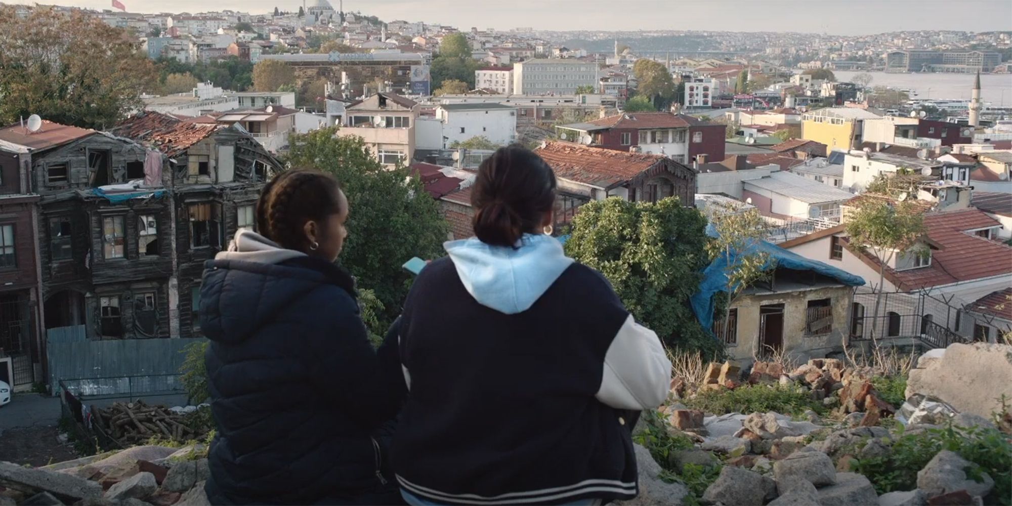 Muna and Doe backs to the audience and facing the town in Brides