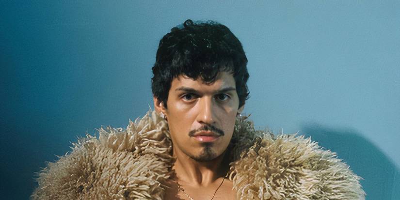 Omar Apollo in an open fur coat, lookng at the camera on his God Said No album cover