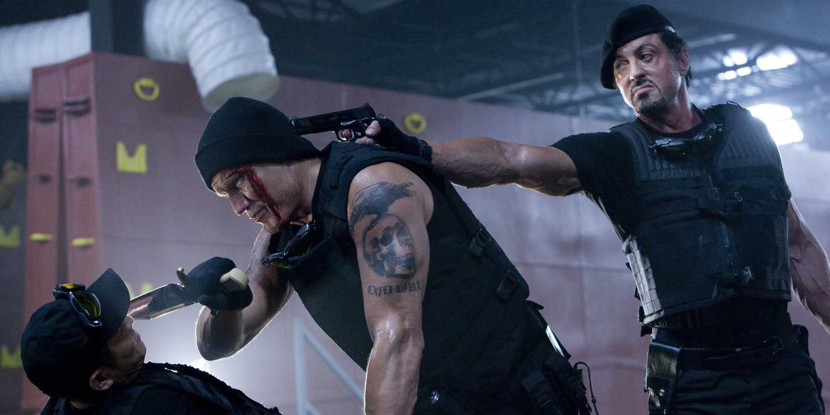 Sylvester Stallone holds Dolph Lundgren at gunpoint holding Jet Li at gunpoint in The Expendables 2010