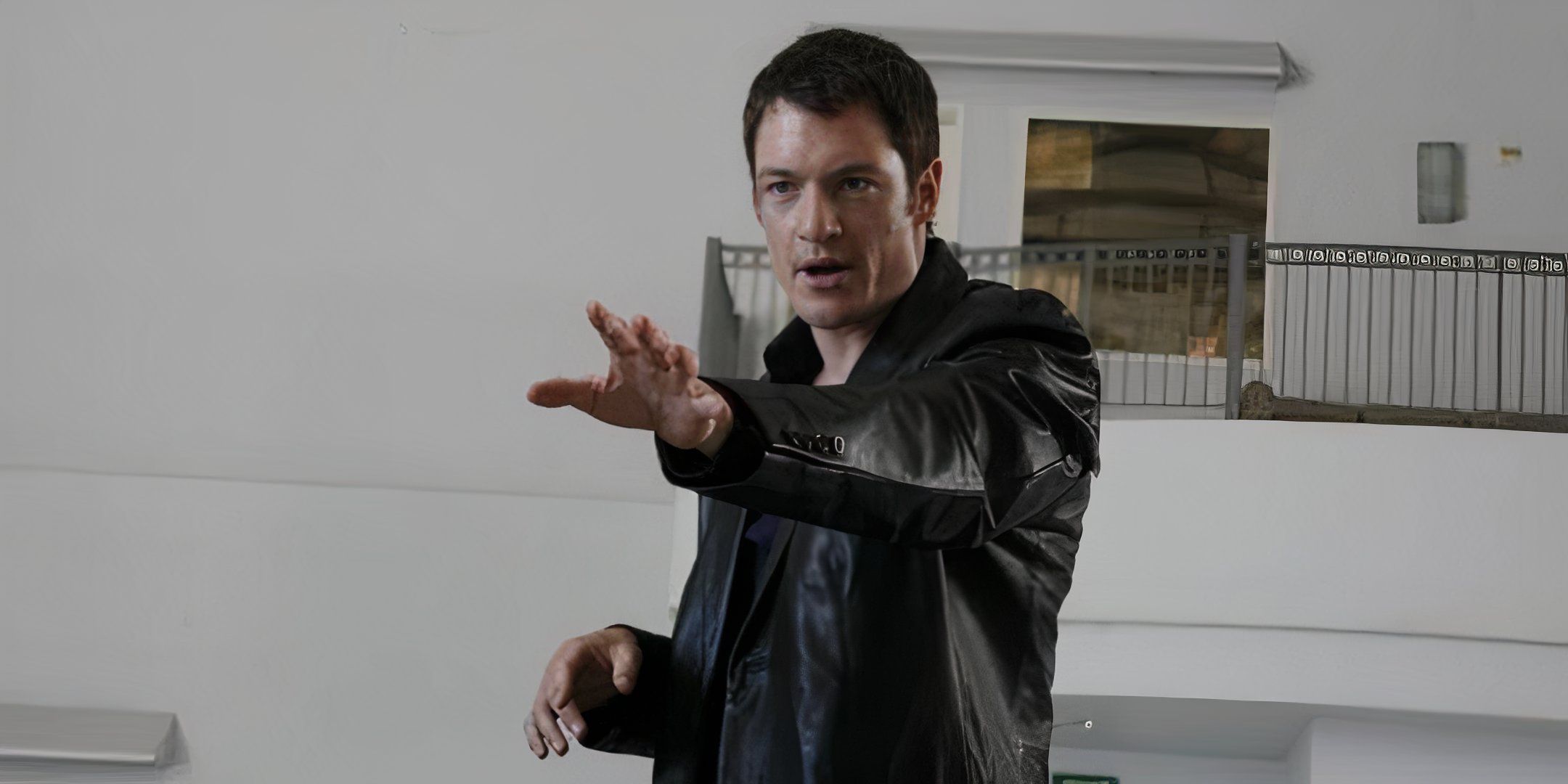 Tahmoh Penikett estende o braço esquerdo à sua frente. 