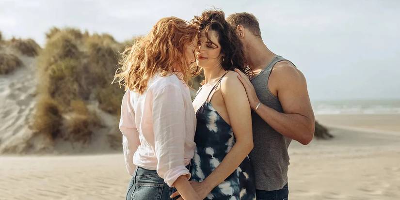 Evie, Becka, and Danny canoodling on the beach in The Couple Next Door