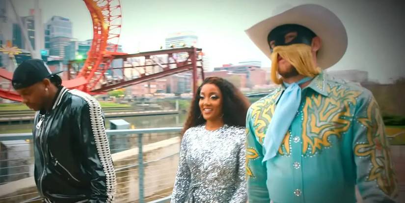 Three costimed contestants walking through a theme park in My Kind of Country.