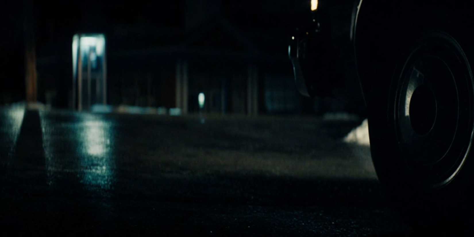 Irving in a phone booth being watched from afar by Burt in his car in Severance