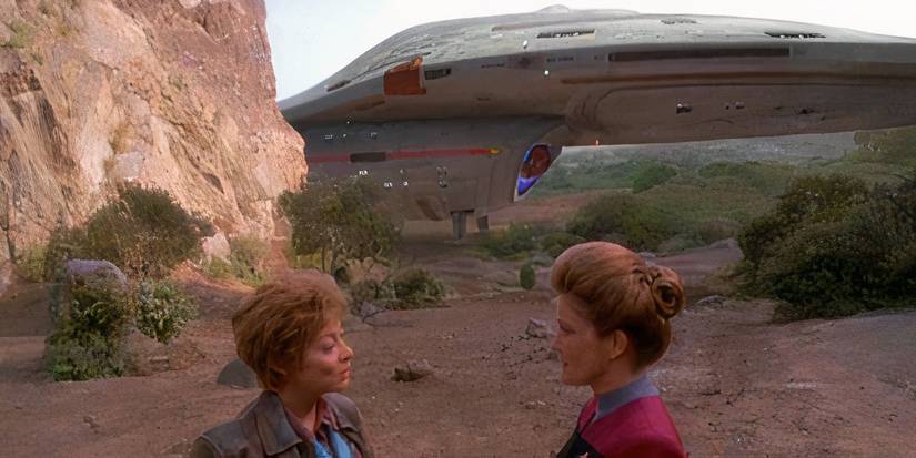 Captain Janeway (Kate Mulgrew) talks to a human in front of a landed starship Voyager.