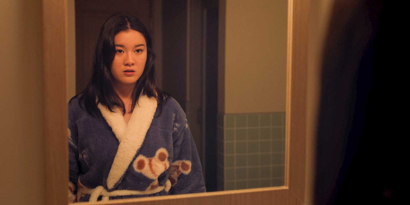 Stella looks in the mirror while wearing a bathrobe in XO, Kitty season 2.
