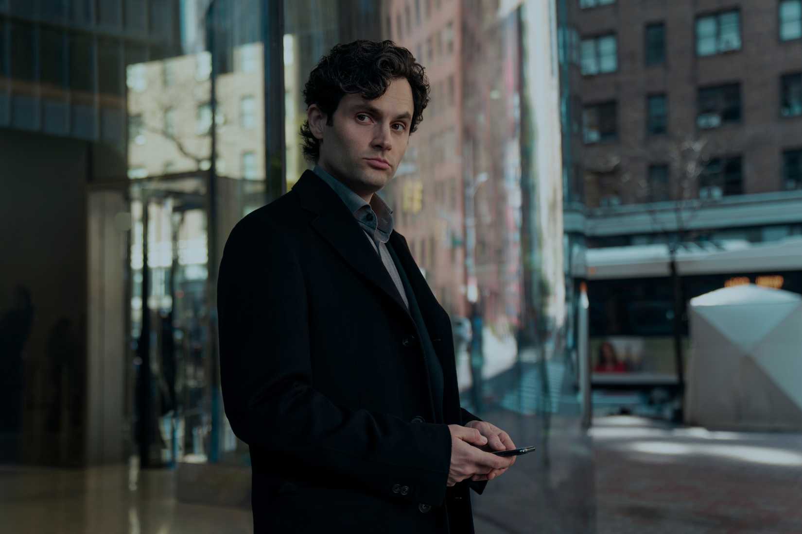 Joe Goldberg holding his phone on a street corner in You season 5