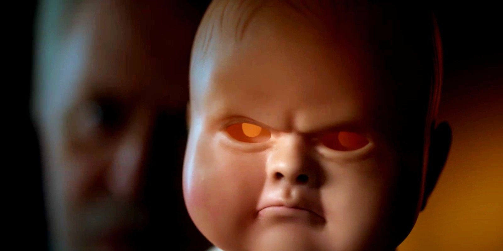 a close-up of the Jenny Pen doll frowning while John Lithgow hovers behind out of focus in The Rule of Jenny Pen