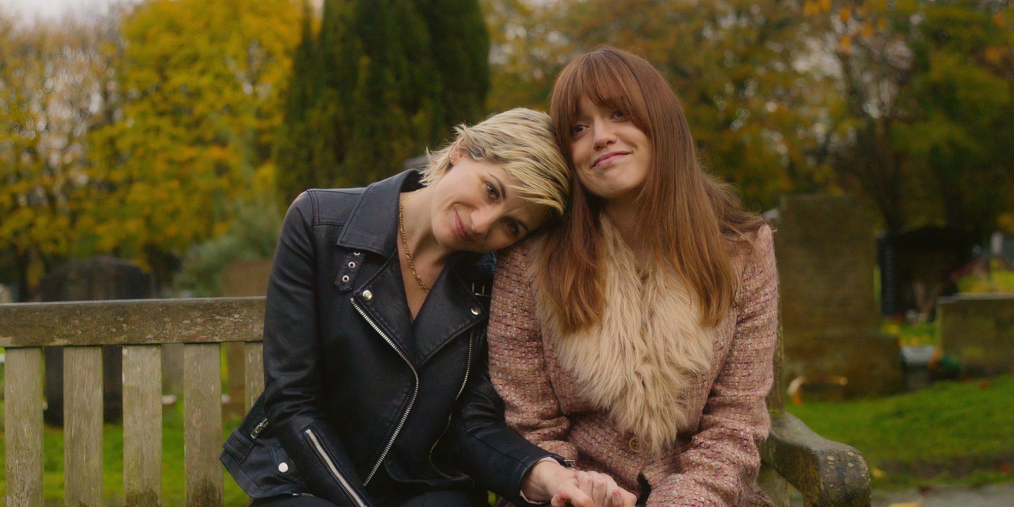 Aimee Lou Wood and Jodie Whittaker leaning on one another while sitting on a bench in Toxic Town