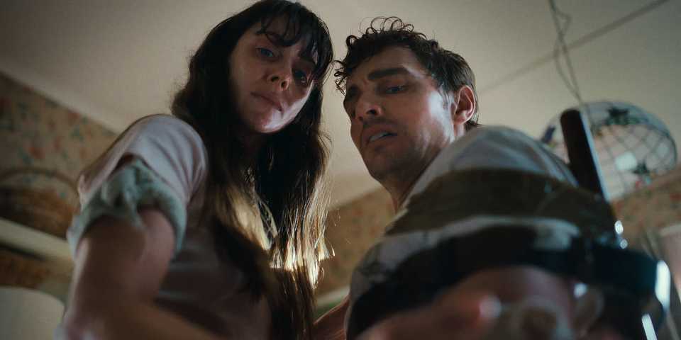 Alison Brie and Dave Franco look down at their arms in Together