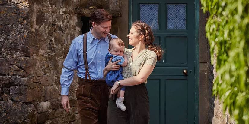 Helen and James camminano con il loro bambino sorridendo tra gli animali