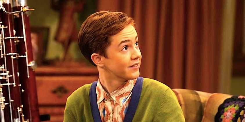 Ames MacNamara's Mark smiles while sitting on the couch in The Conners