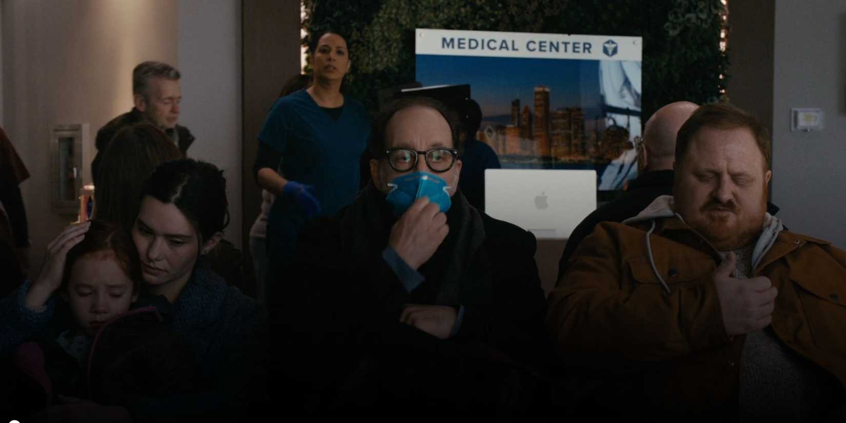 Chicago Med An inspector sitting in the waiting room wearing a blue N-95 mask