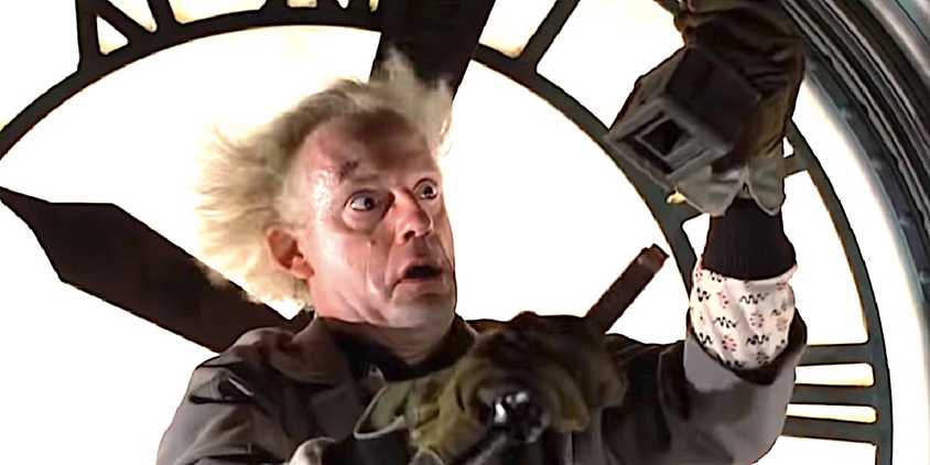 Christopher Lloyd's Doc Brown links up two electrical adaptors standing at a clock tower in Back to the Future's ending