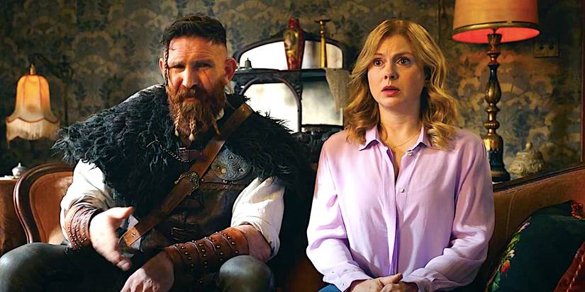 Devan Chandler Long's Thor and Rose McIver's Sam sit on a couch in Ghosts season 4 episode 11